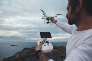 Professional drone pilot operating a camera drone over water for aerial footage